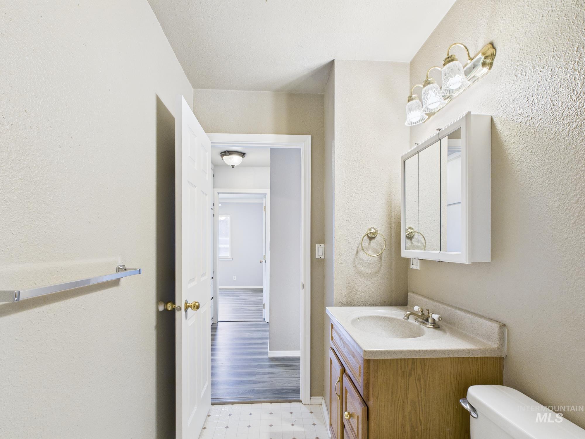 Half bathroom featuring a textured wall, vanity, and light flooring