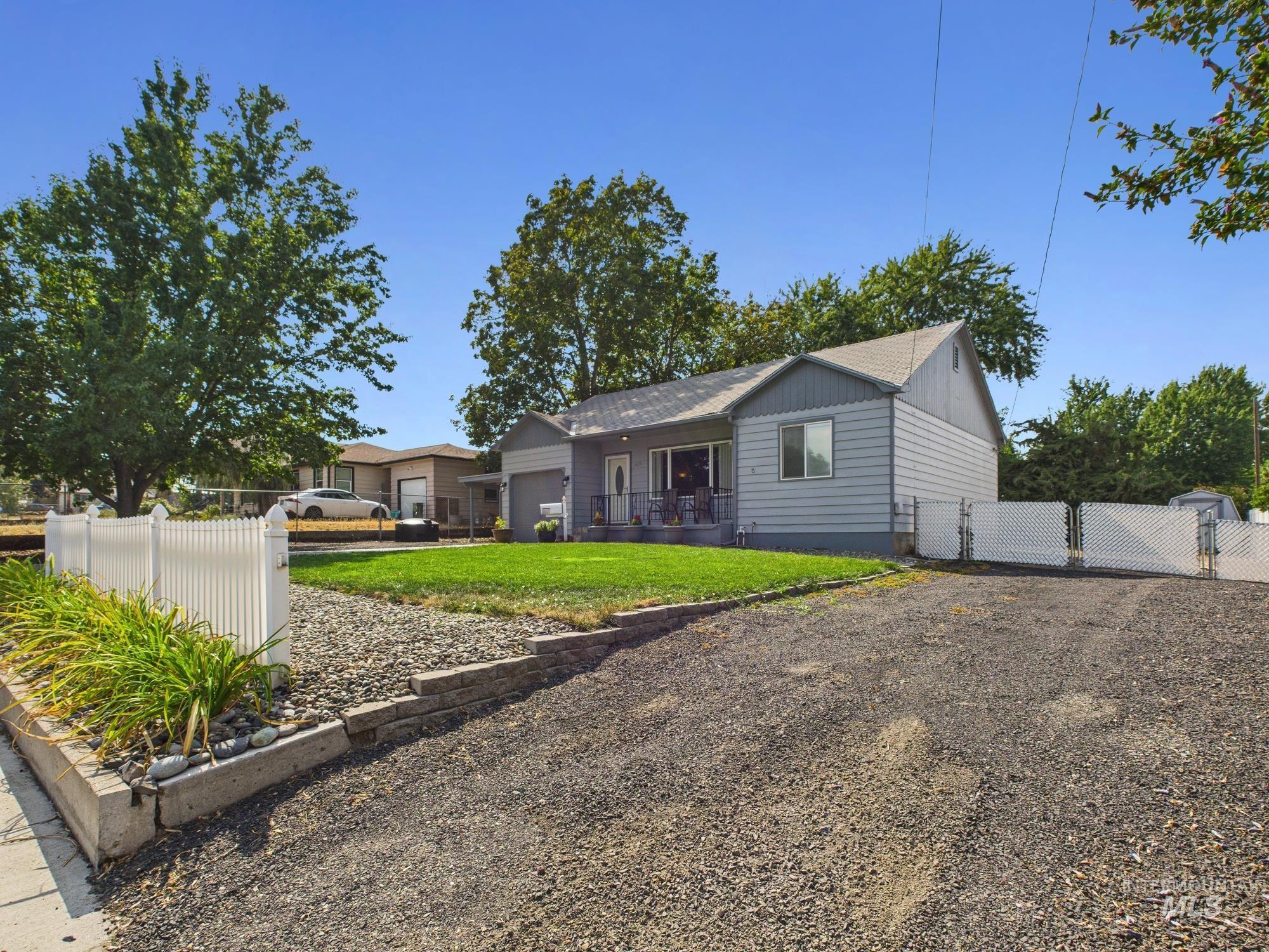 Ranch-style house featuring a fenced front yard, a gate, a garage, and a shingled roof