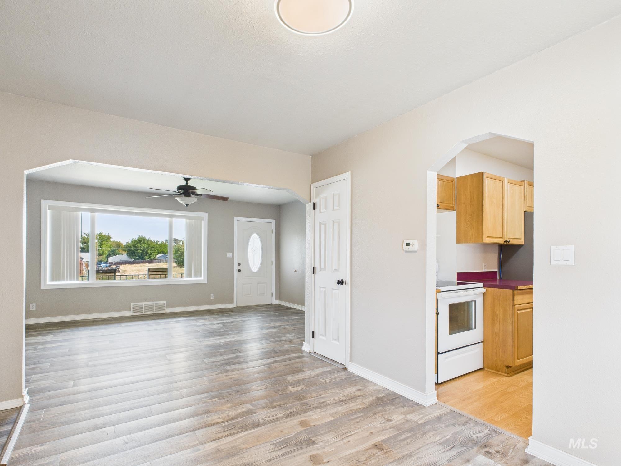 Unfurnished living room with arched walkways, a ceiling fan, and light wood finished floors