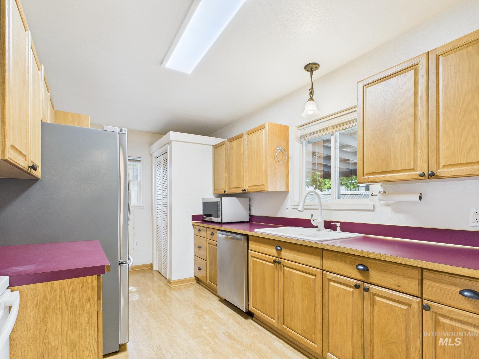 Kitchen featuring pendant lighting, stainless steel appliances, light wood-style floors, and light brown cabinetry