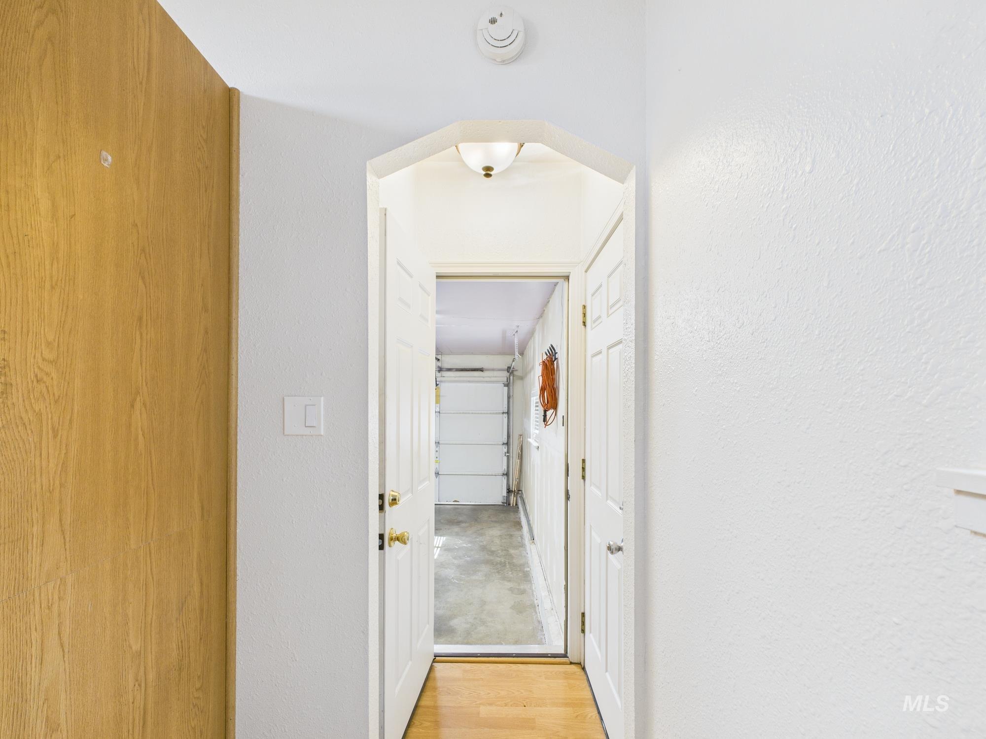 Hall with light wood-style flooring, a textured wall, and arched walkways
