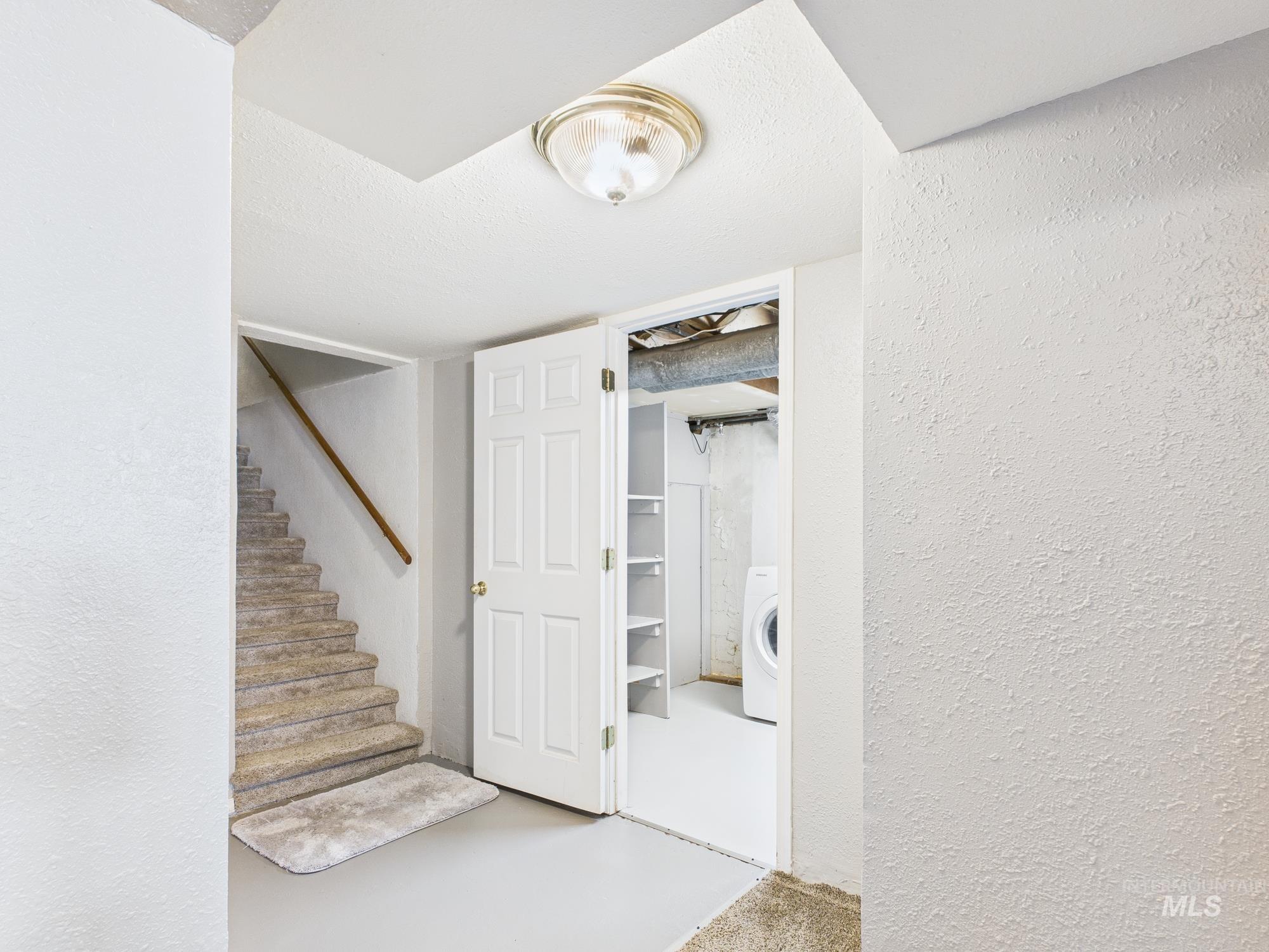 Finished basement with a textured wall and washer / clothes dryer