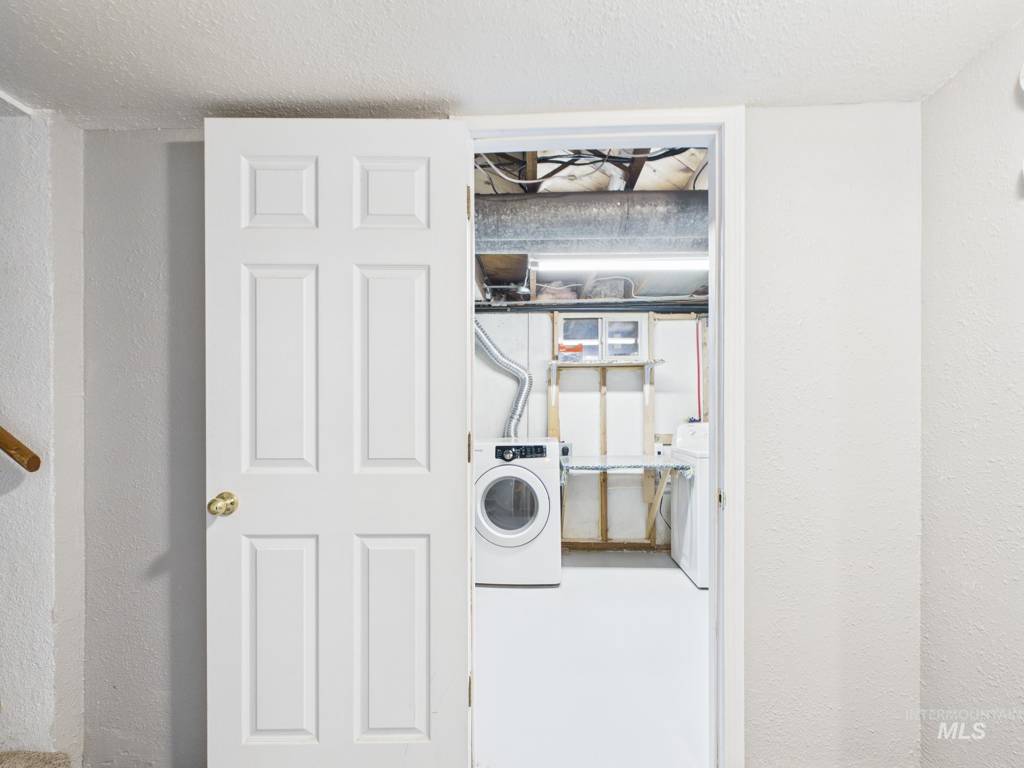 Laundry room featuring washer / dryer, a textured wall, and a textured ceiling