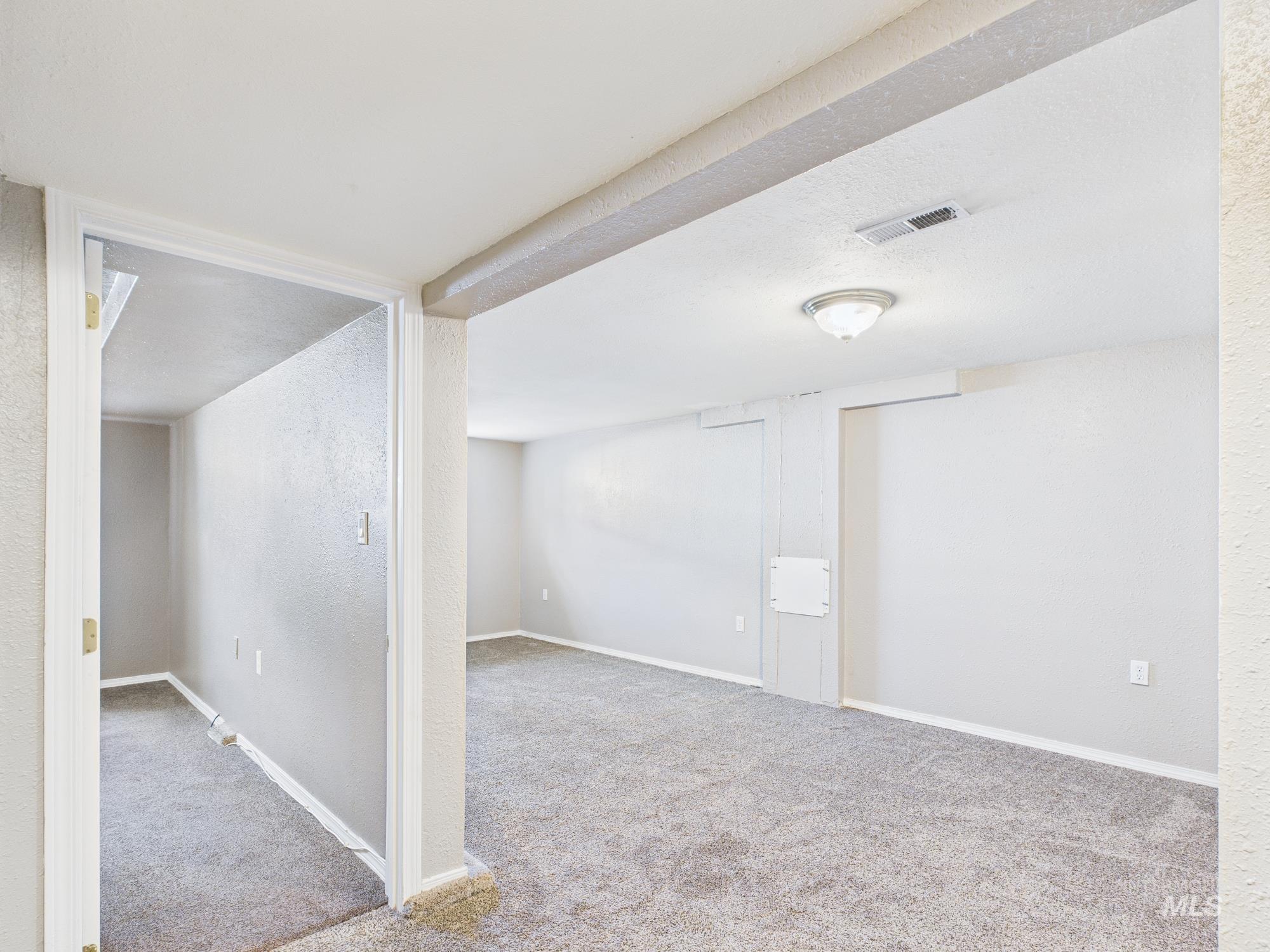Basement featuring light colored carpet, a textured wall, and a textured ceiling