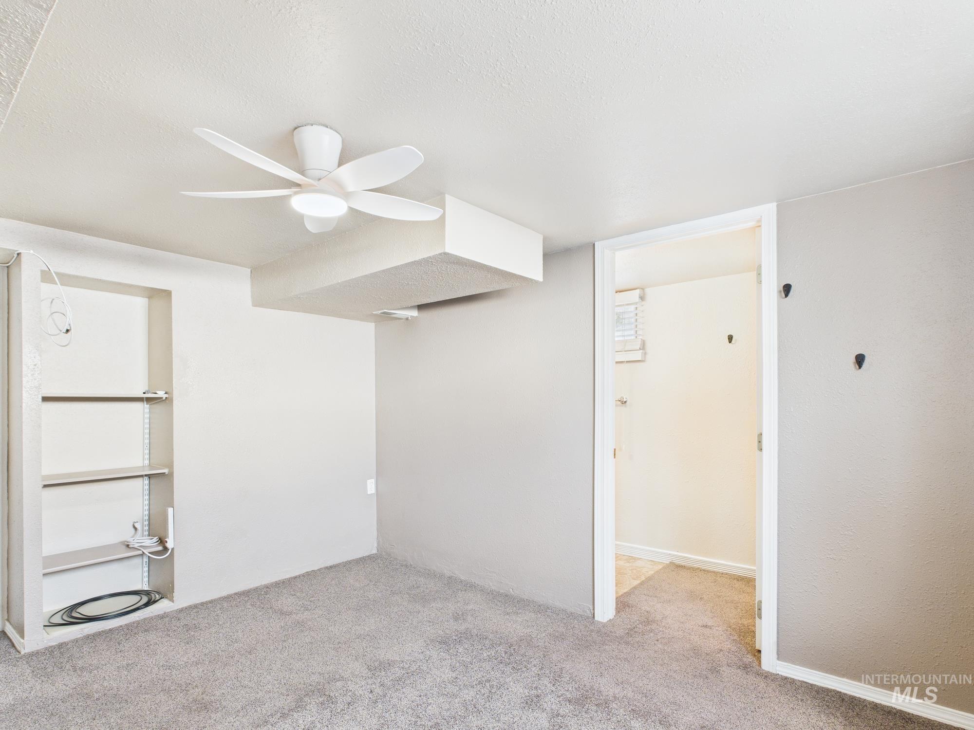 Unfurnished bedroom with light colored carpet, ceiling fan, and a textured ceiling