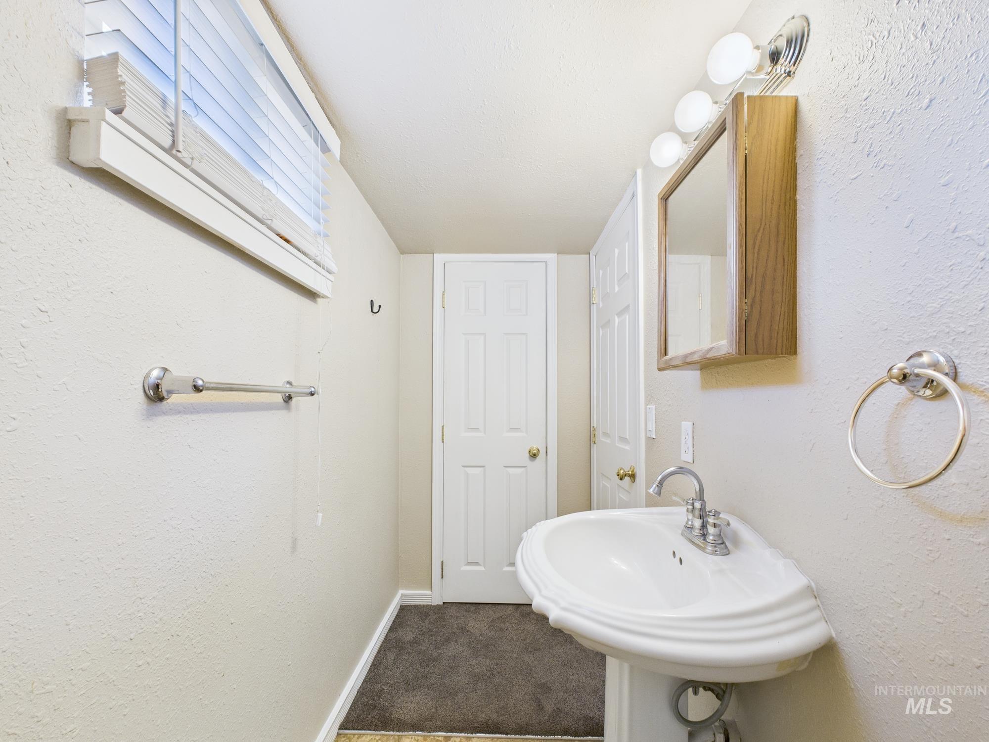 Bathroom featuring a textured wall and baseboards