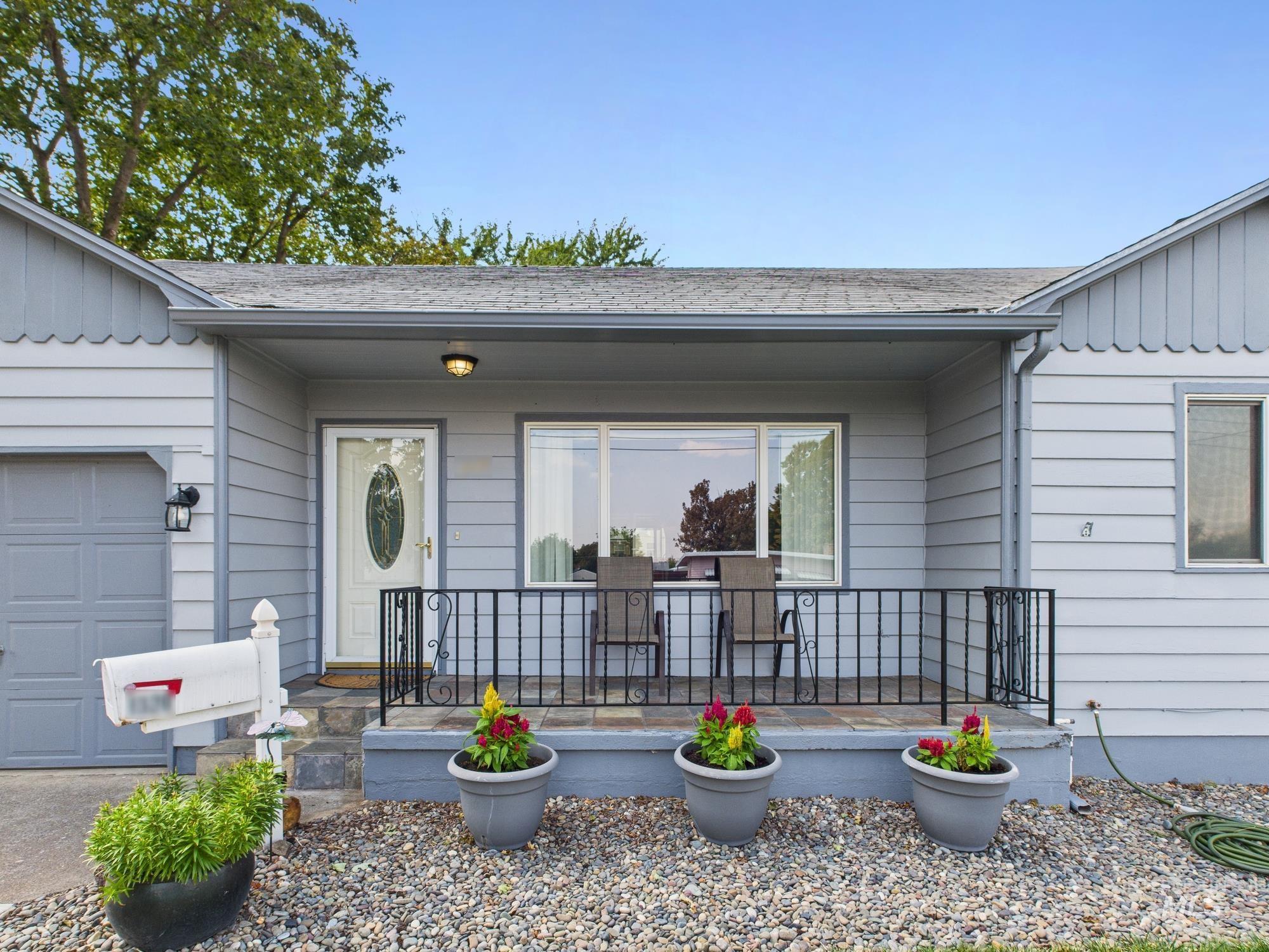 Entrance to property with a shingled roof, a garage, and covered porch