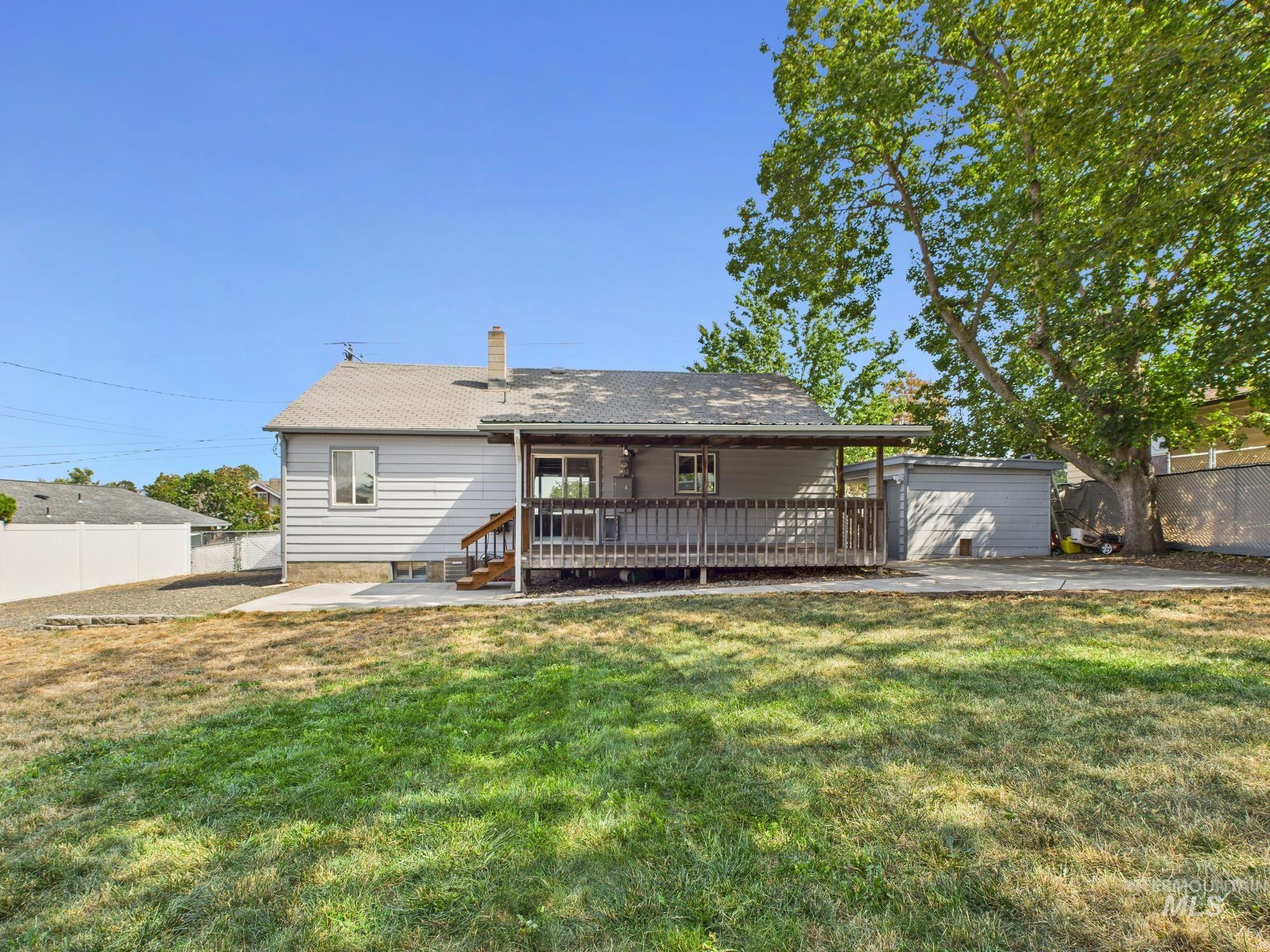 Rear view of house featuring a patio area, a deck, and a chimney