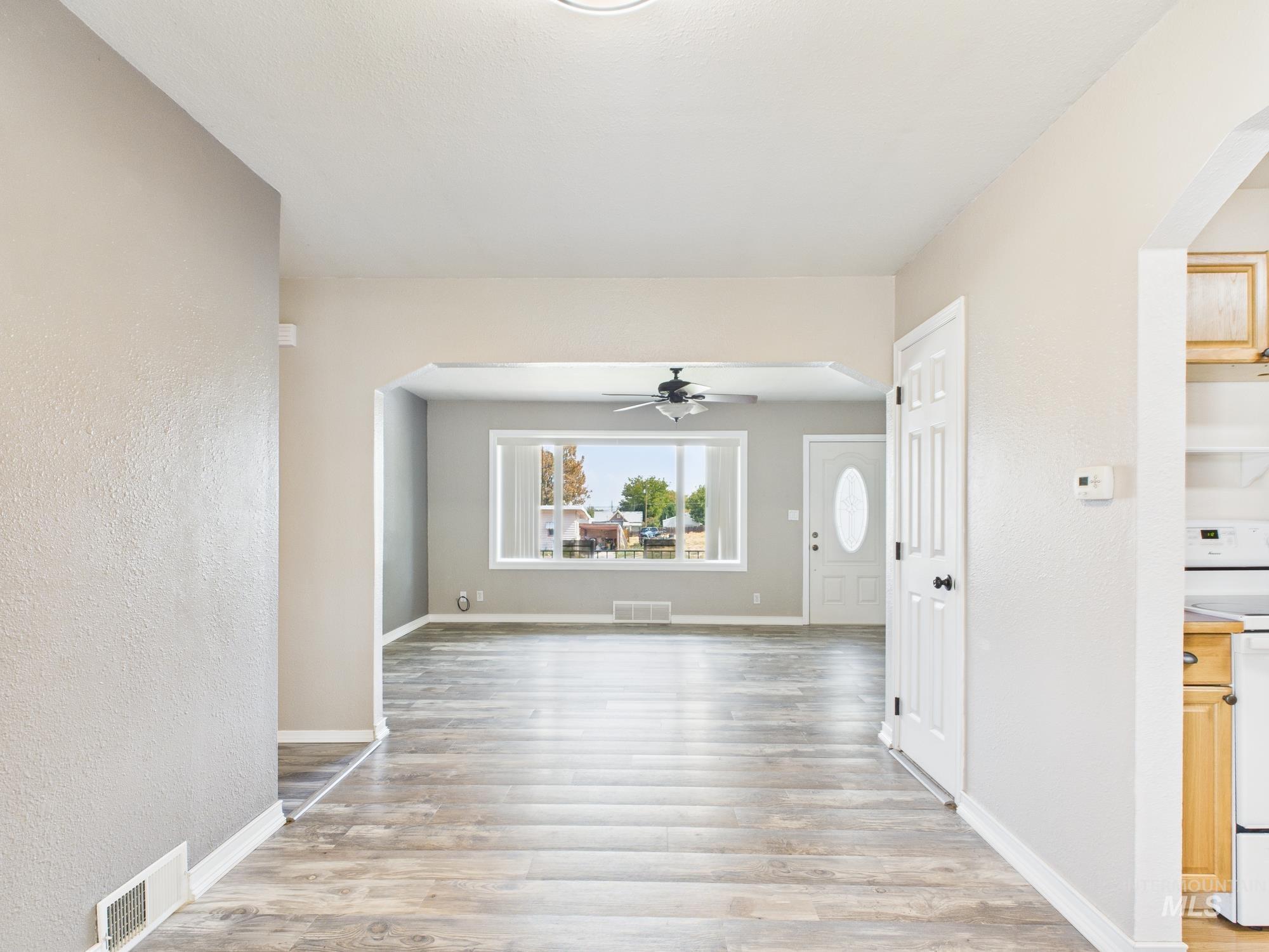 Hall with arched walkways, light wood-style flooring, and a textured wall