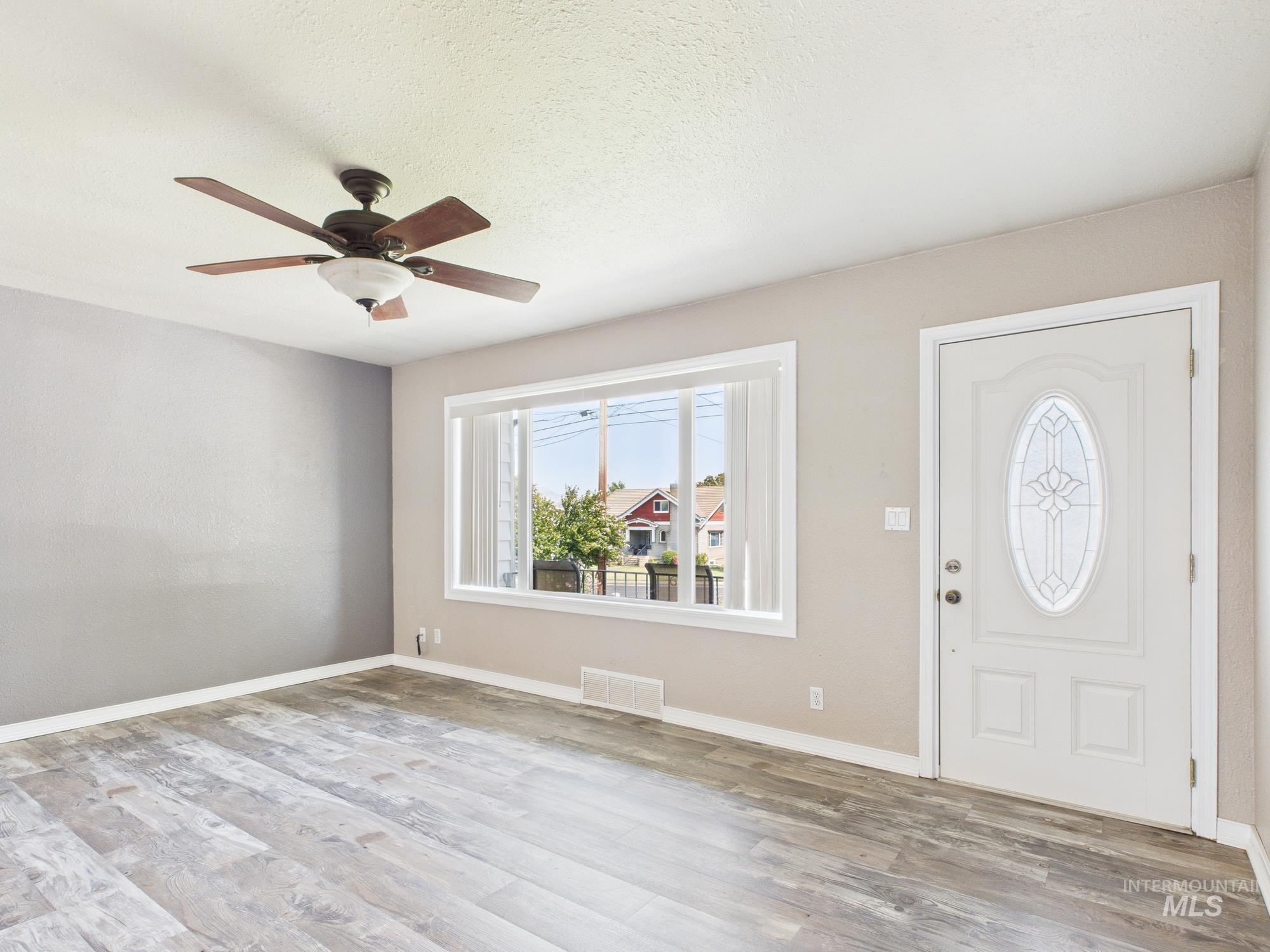 Entryway featuring a textured ceiling, light wood-style floors, and a ceiling fan