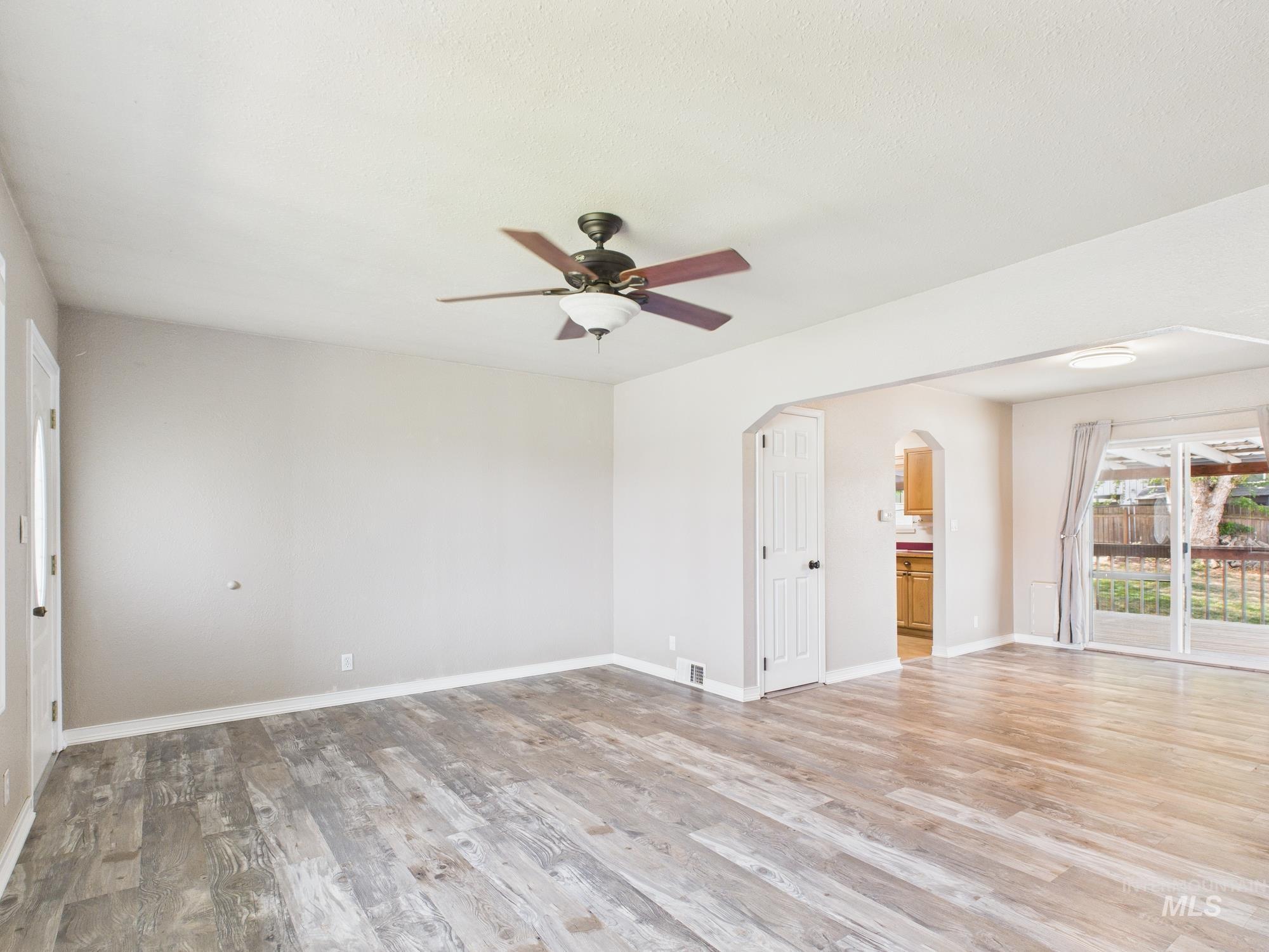 Unfurnished room with light wood-style floors, ceiling fan, and arched walkways