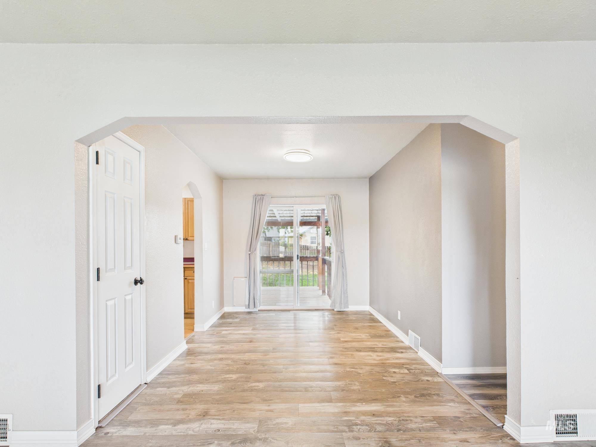 Unfurnished dining area featuring arched walkways and light wood-type flooring