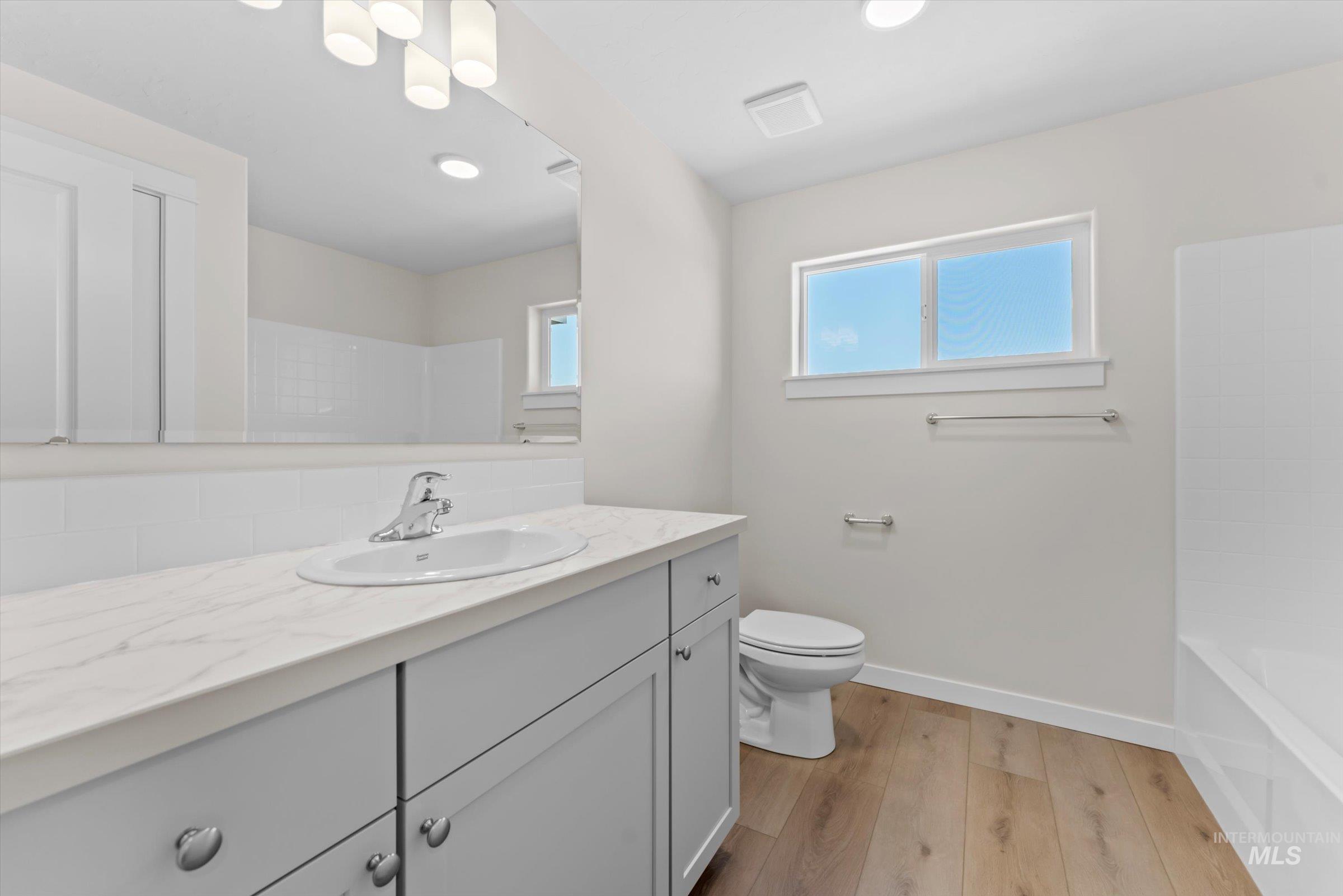 Bathroom with vanity, light wood-style floors, shower / washtub combination, and recessed lighting
