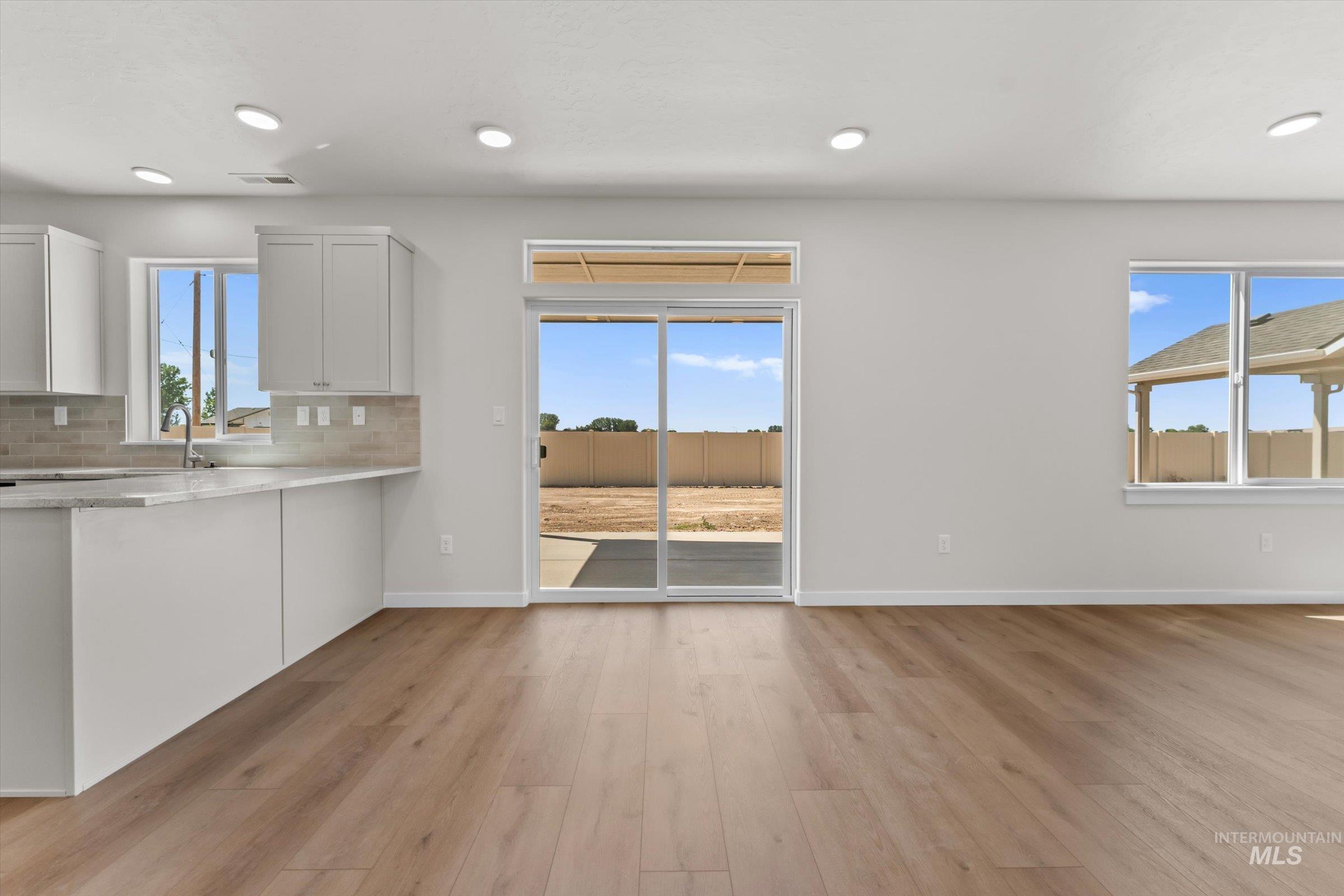 Kitchen with light wood-style flooring, healthy amount of natural light, decorative backsplash, and recessed lighting