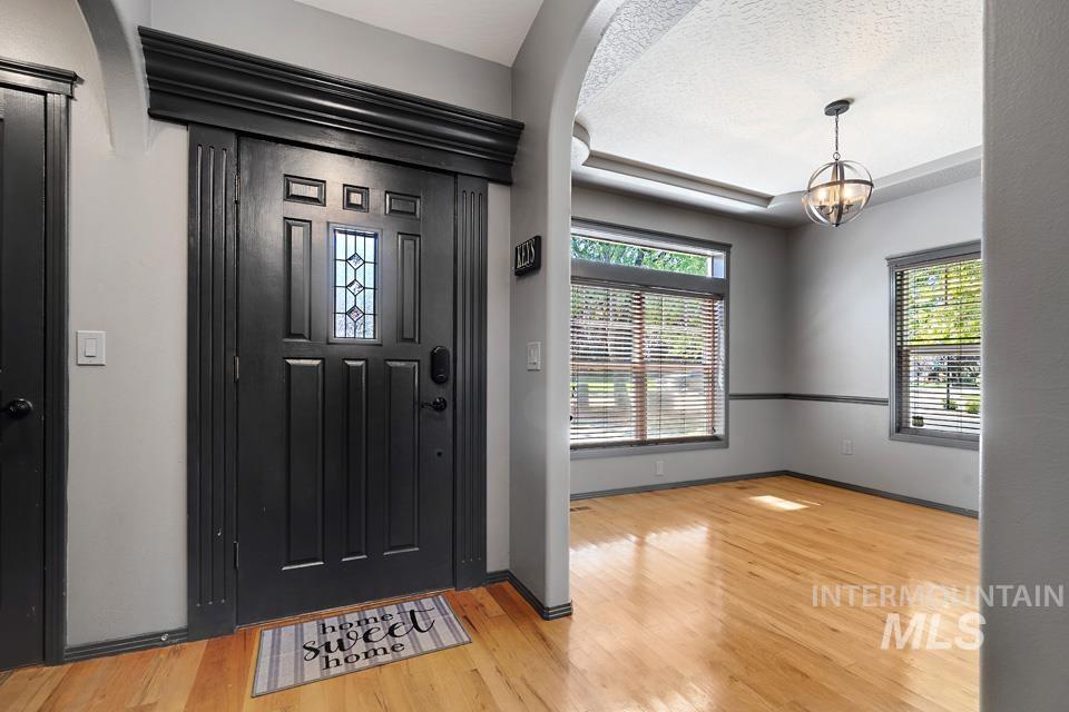 Foyer featuring healthy amount of natural light, light wood-style floors, a chandelier, and a textured ceiling