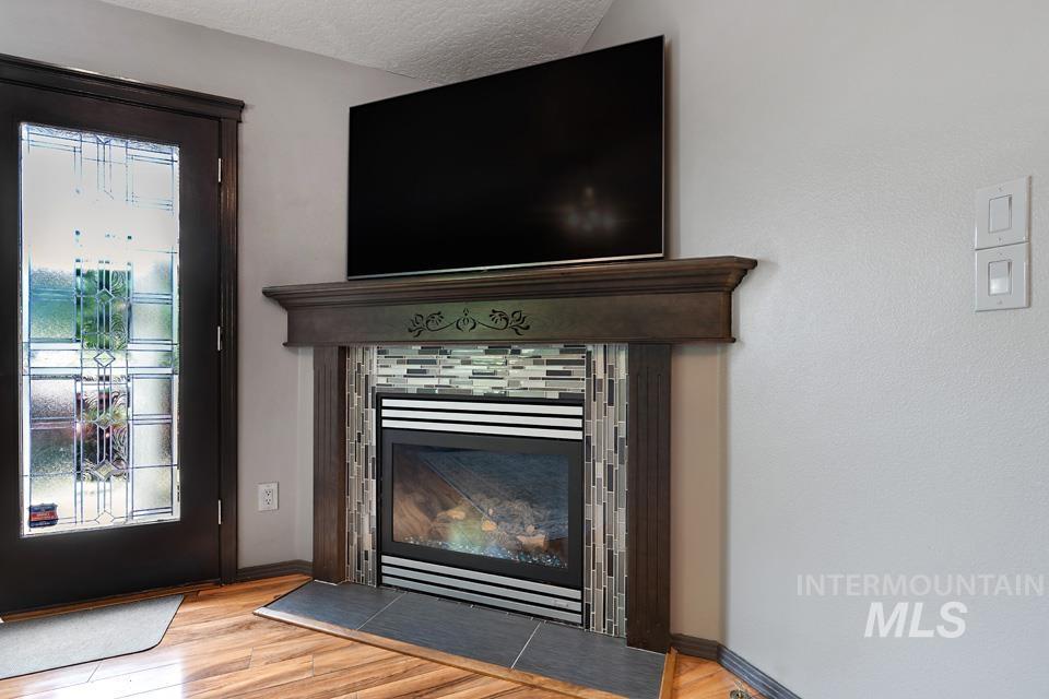 Detailed view of wood finished floors, a textured ceiling, and a tile fireplace