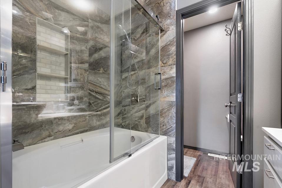 Bathroom featuring enclosed tub / shower combo, vanity, and dark wood finished floors