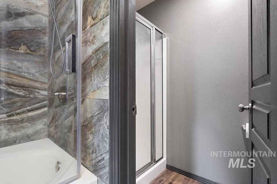 Bathroom featuring a marble finish shower, wood finished floors, and a bath