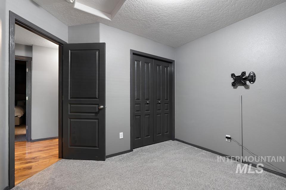 Unfurnished bedroom featuring a textured ceiling, light carpet, and a closet