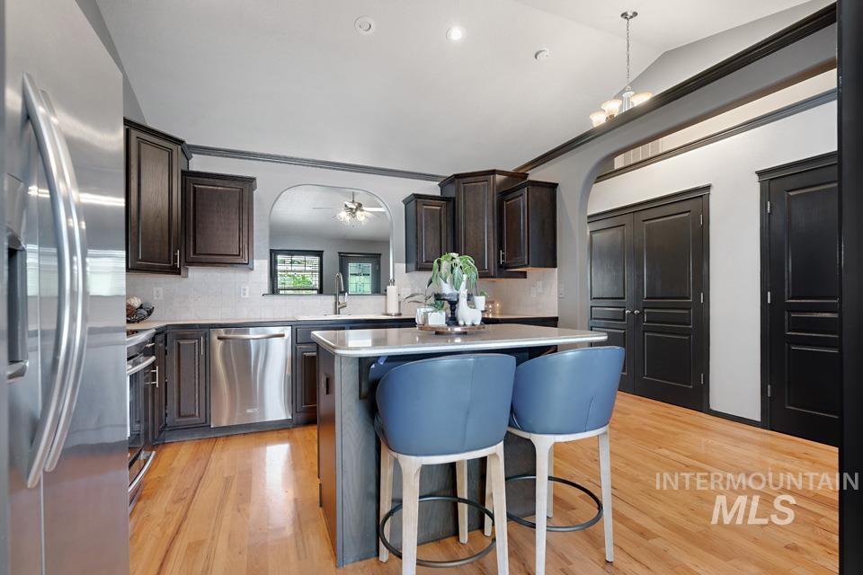Kitchen featuring a kitchen breakfast bar, stainless steel appliances, decorative backsplash, a center island, and light wood-style floors