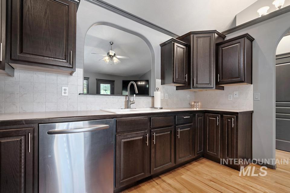 Kitchen with dark brown cabinetry, arched walkways, and a ceiling fan