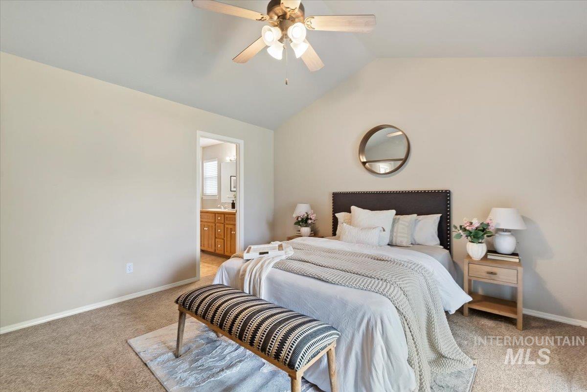 Bedroom with light carpet, lofted ceiling, ceiling fan, and ensuite bathroom