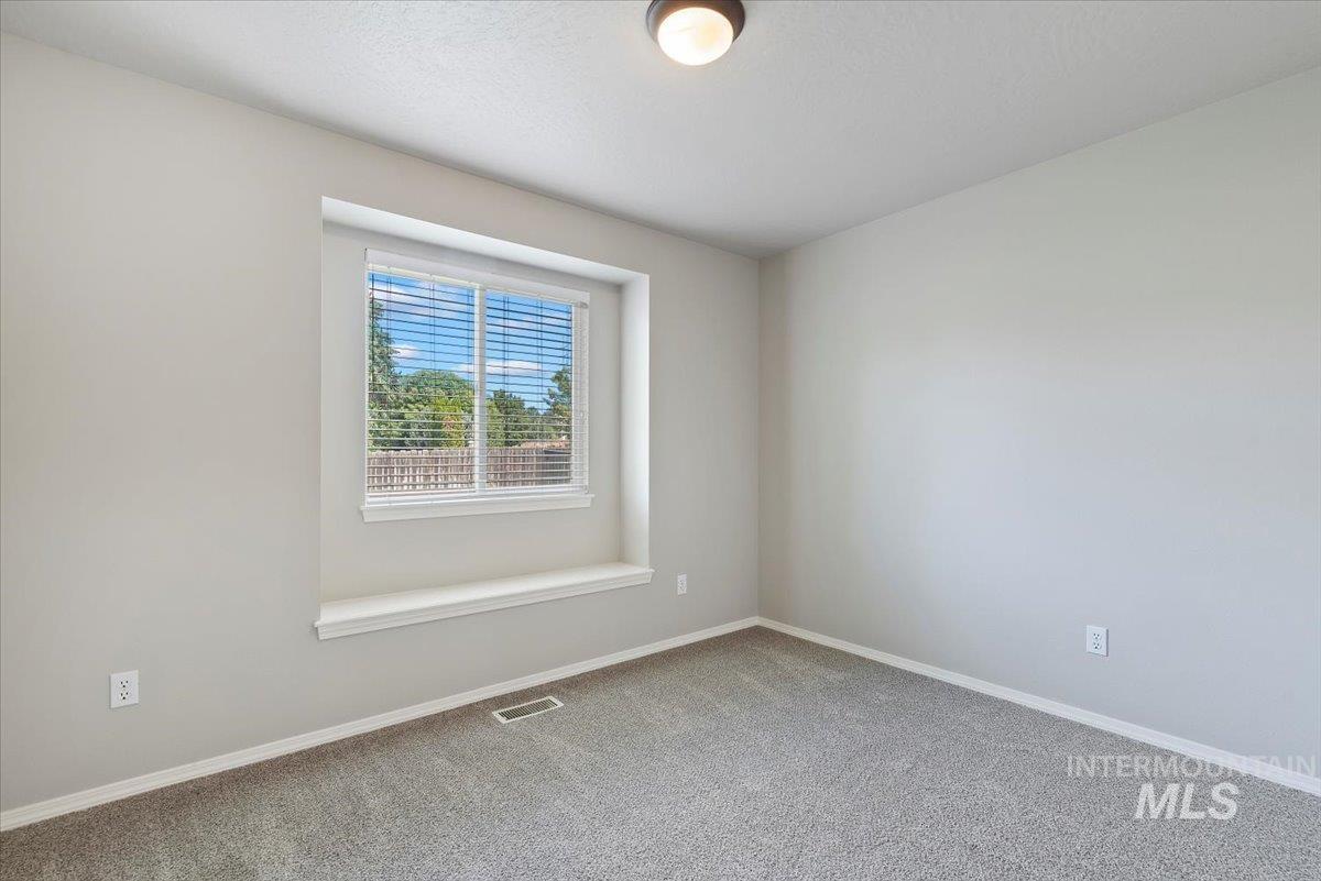 Carpeted spare room featuring baseboards