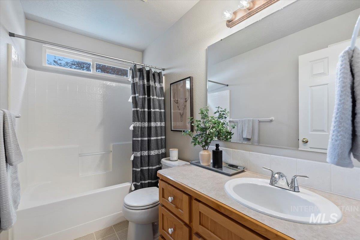 Bathroom featuring shower / tub combo, vanity, and light tile patterned flooring