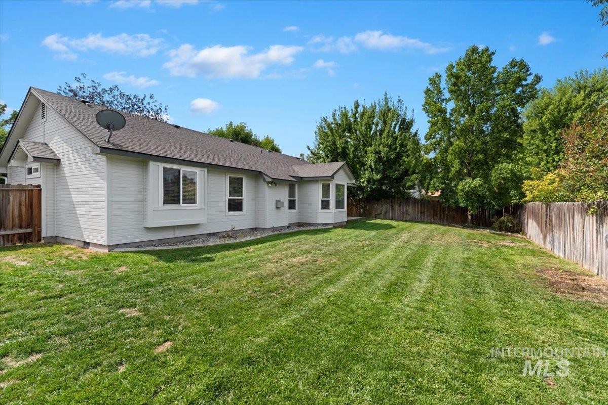 Back of house with a fenced backyard and roof with shingles