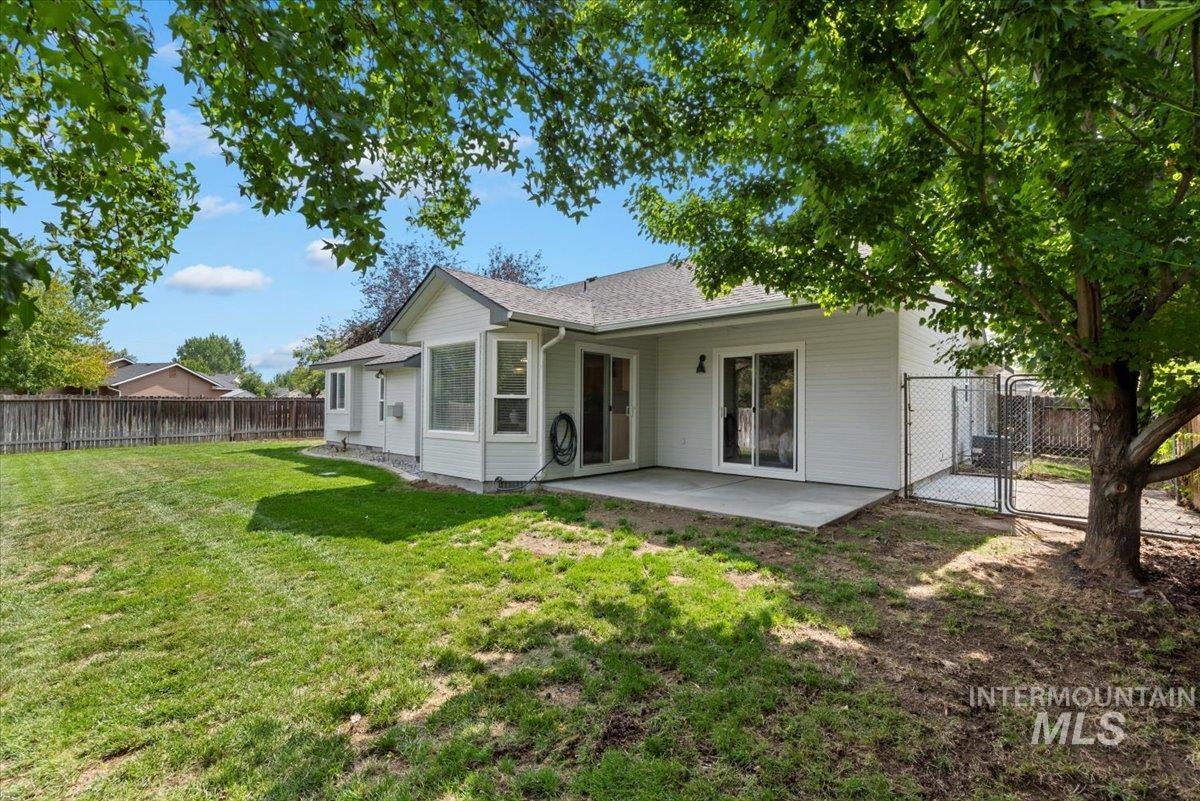 Back of property featuring a fenced backyard, a patio area, a gate, and a shingled roof