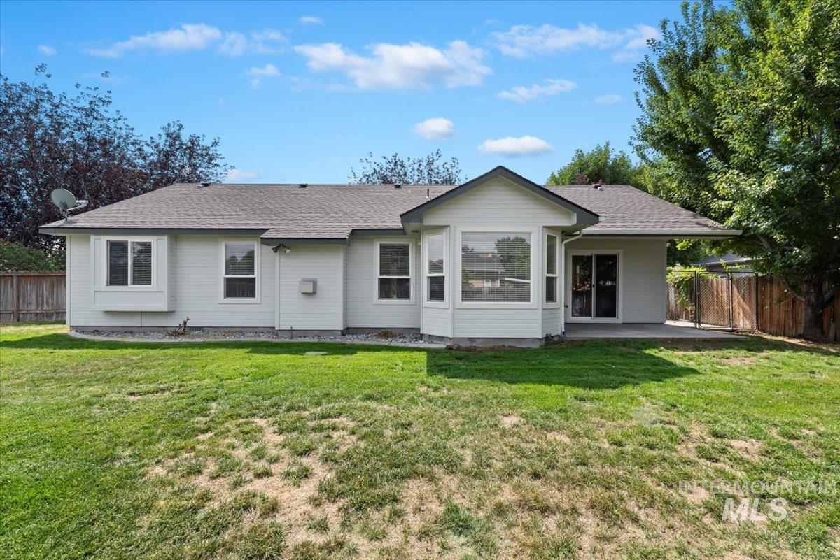 Rear view of house with a shingled roof and a patio