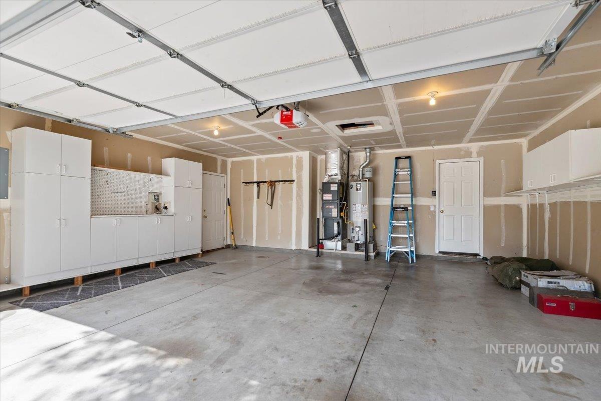 Garage featuring gas water heater, a garage door opener, and electric panel
