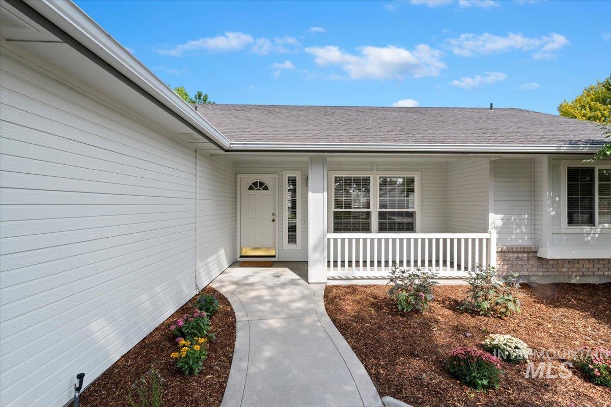 Property entrance with roof with shingles, brick siding, and a porch