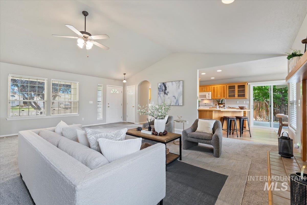 Living room with vaulted ceiling, arched walkways, ceiling fan, and recessed lighting