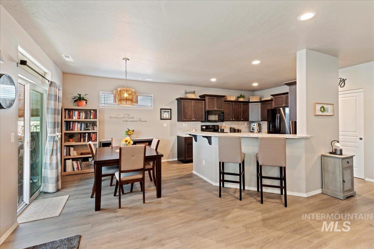 Dining area with light wood finished floors and recessed lighting