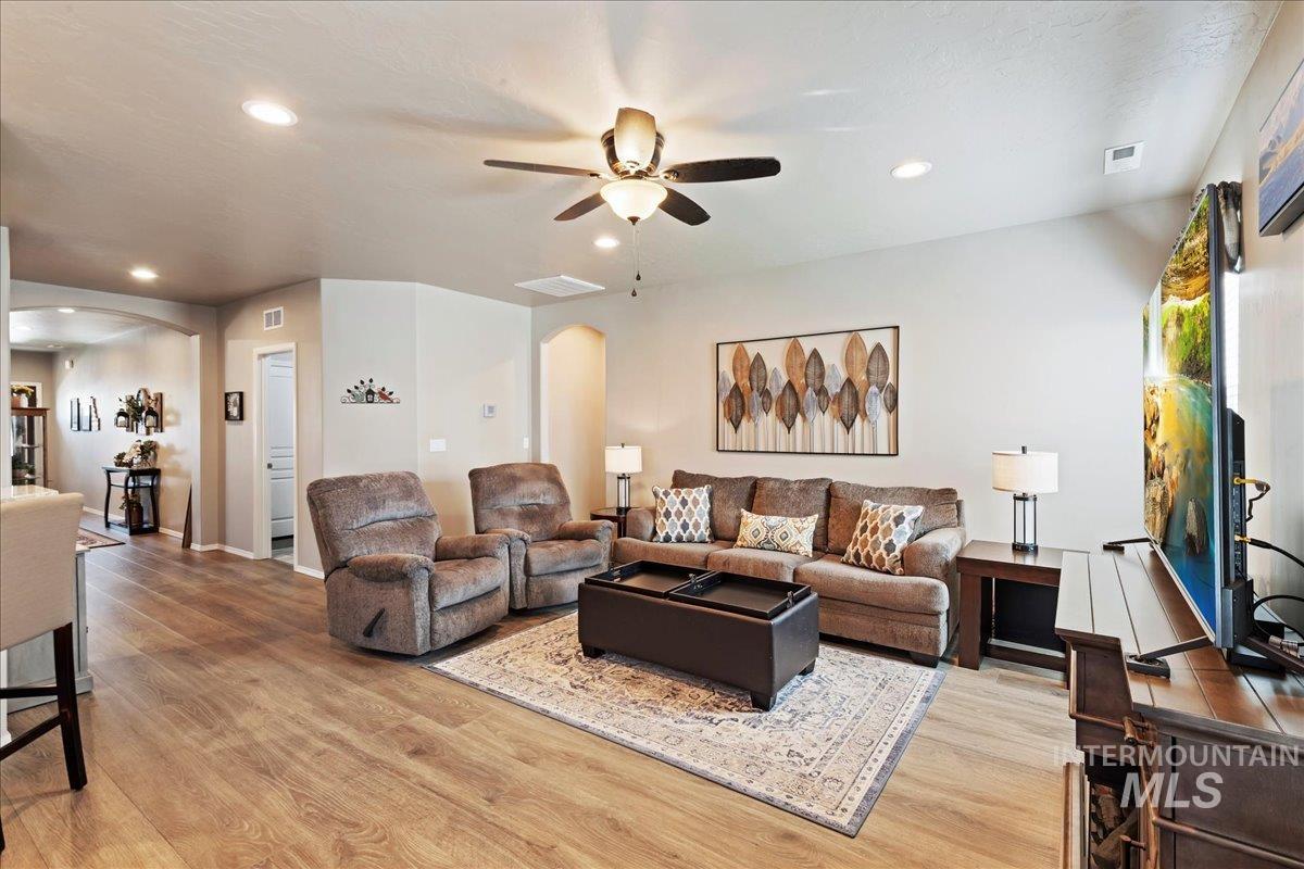 Living room featuring arched walkways, recessed lighting, light wood-style flooring, and ceiling fan