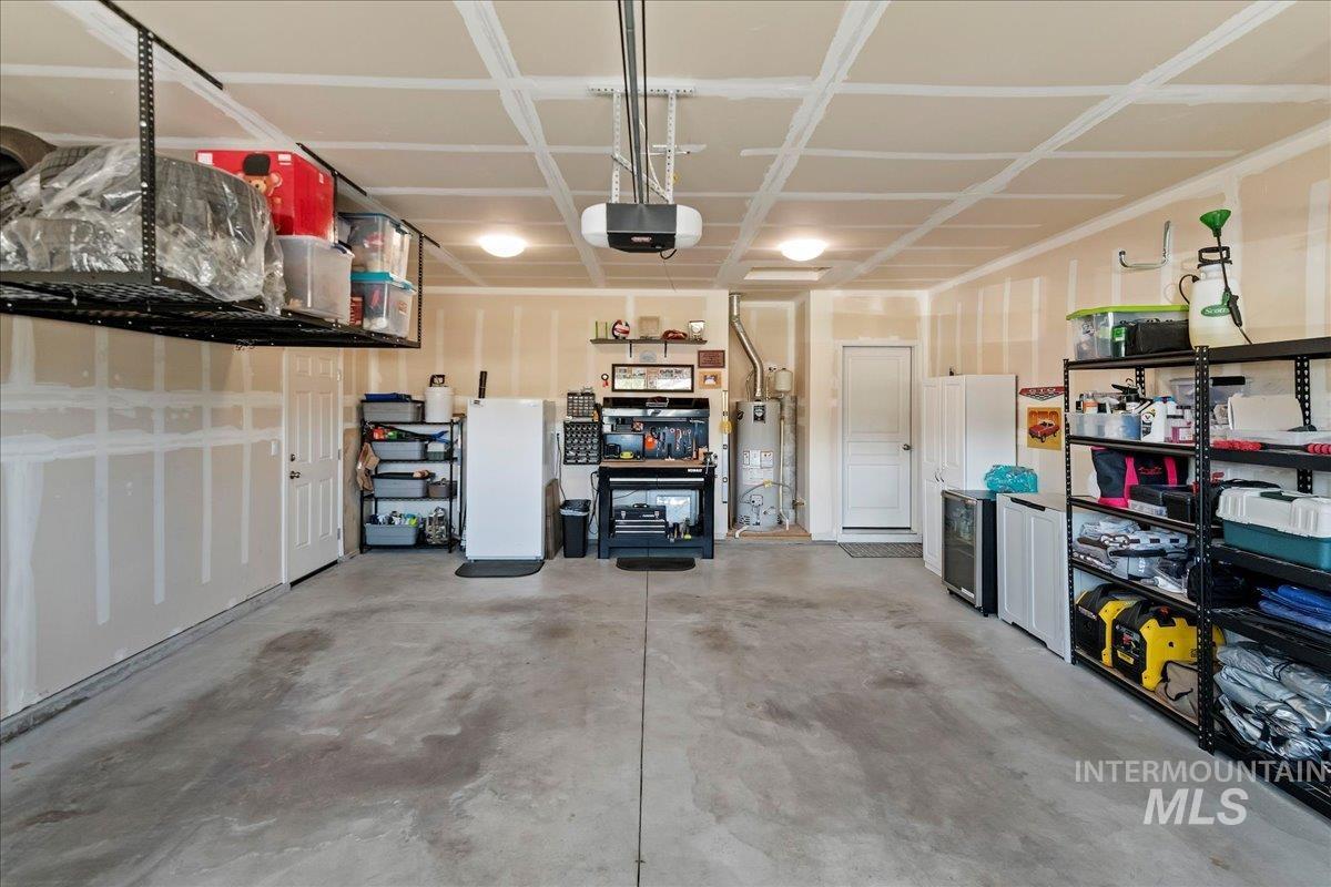 Garage with freestanding refrigerator, water heater, and a garage door opener