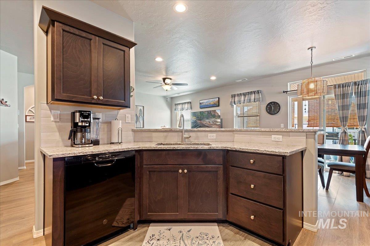 Kitchen featuring dark brown cabinetry, a peninsula, dishwasher, recessed lighting, and a textured ceiling