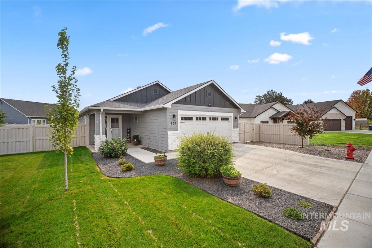 View of front facade with board and batten siding, covered porch, concrete driveway, and an attached garage