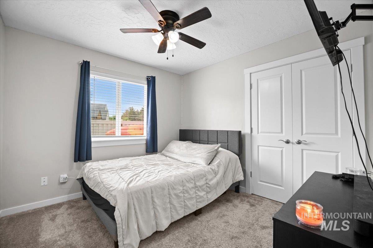 Bedroom with a textured ceiling, carpet flooring, ceiling fan, and a closet