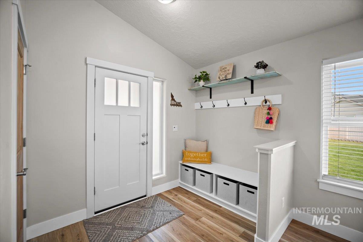 Mudroom featuring light wood-type flooring, lofted ceiling, and a textured ceiling