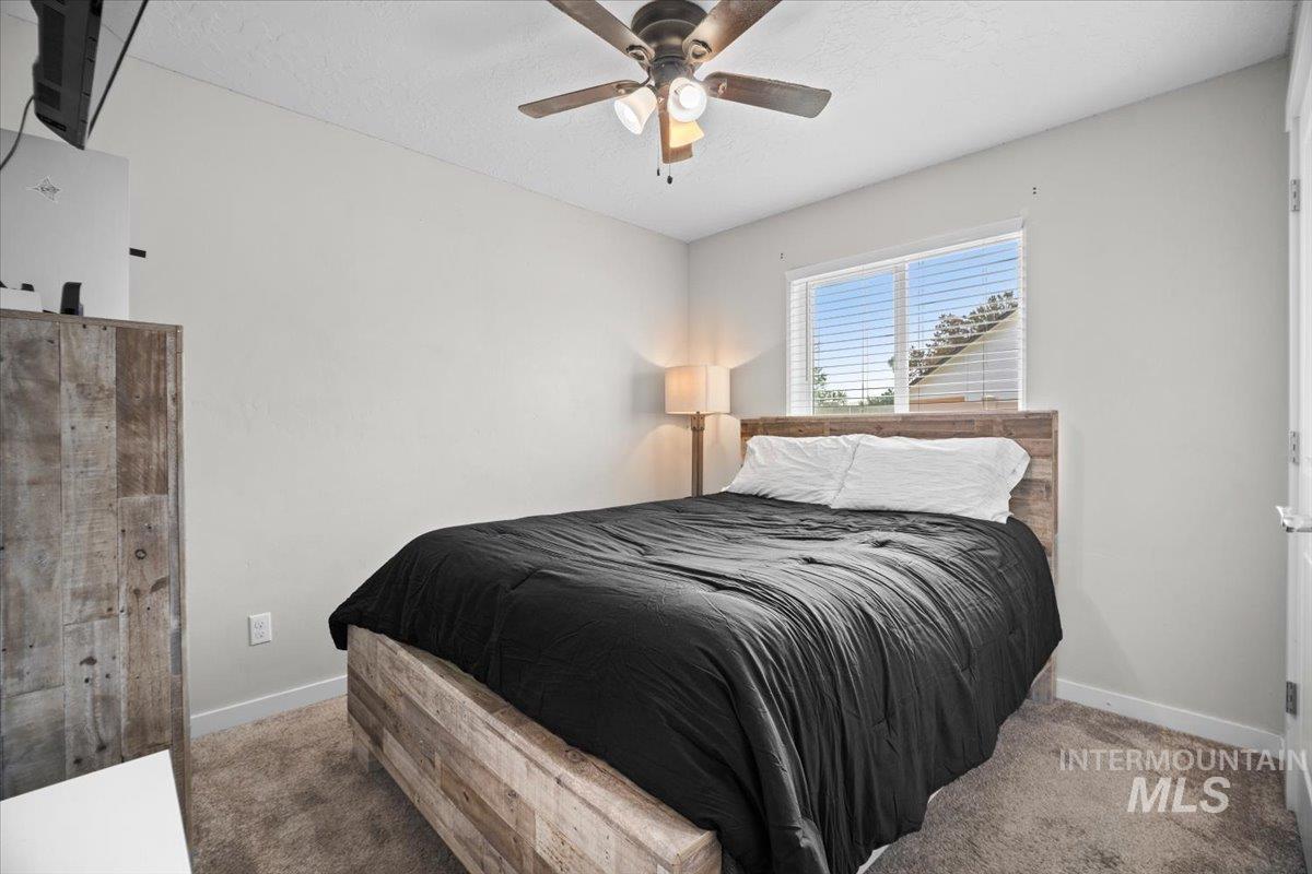Bedroom with carpet floors, a textured ceiling, and a ceiling fan