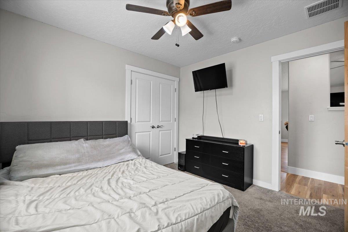 Carpeted bedroom with a textured ceiling, ceiling fan, and a closet