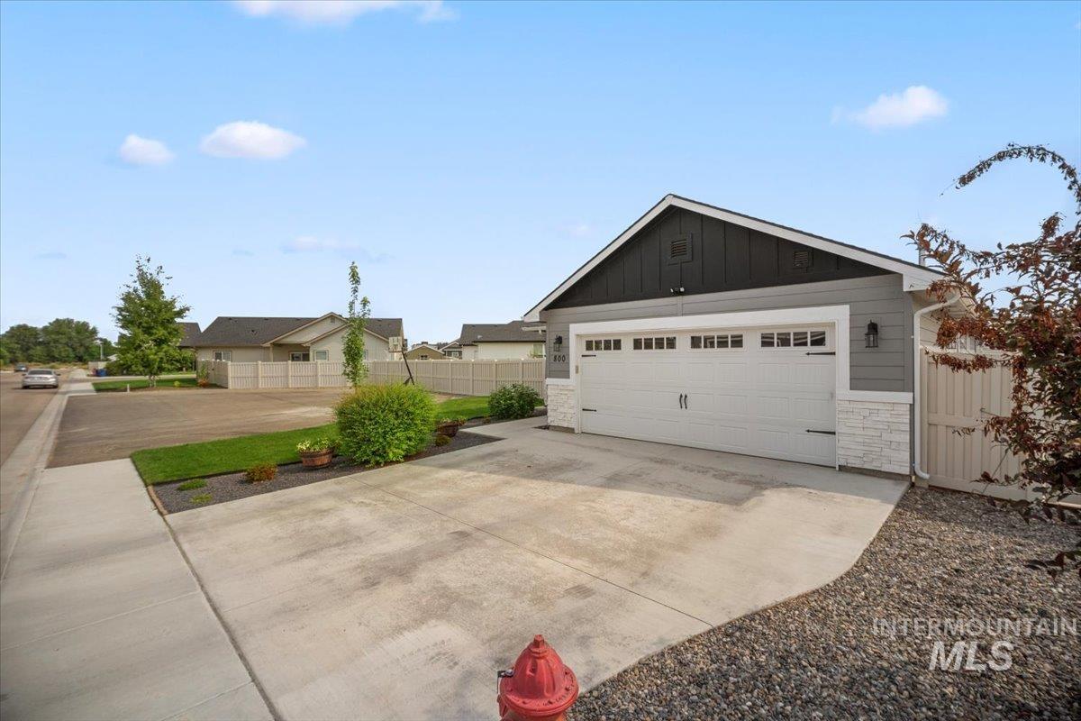 View of front of property with stone siding, board and batten siding, a garage, driveway, and an outdoor structure