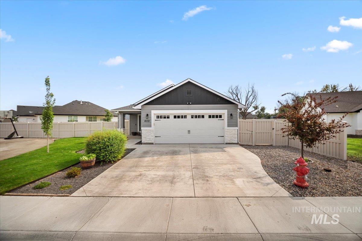 Single story home with stone siding, concrete driveway, a gate, and a garage