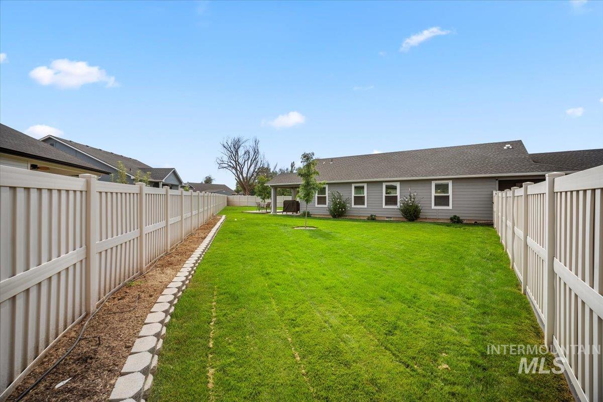 Back of property with a fenced backyard, a gazebo, and roof with shingles