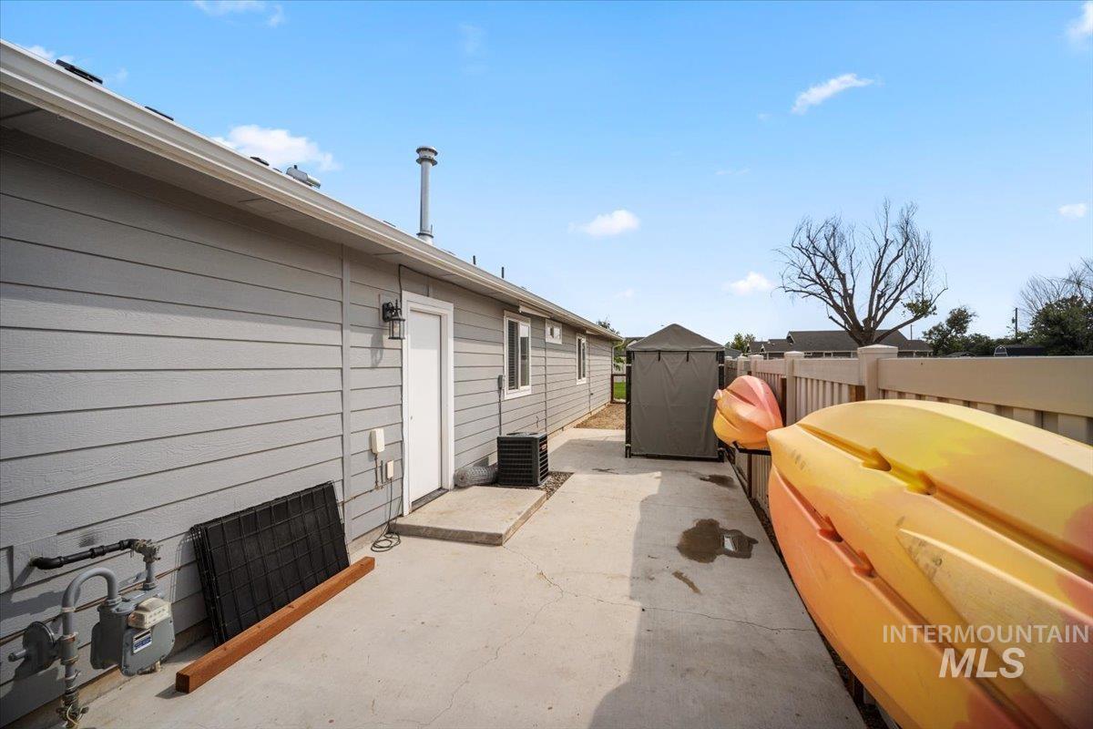 View of side of property with a patio area, a fenced backyard, and a storage shed