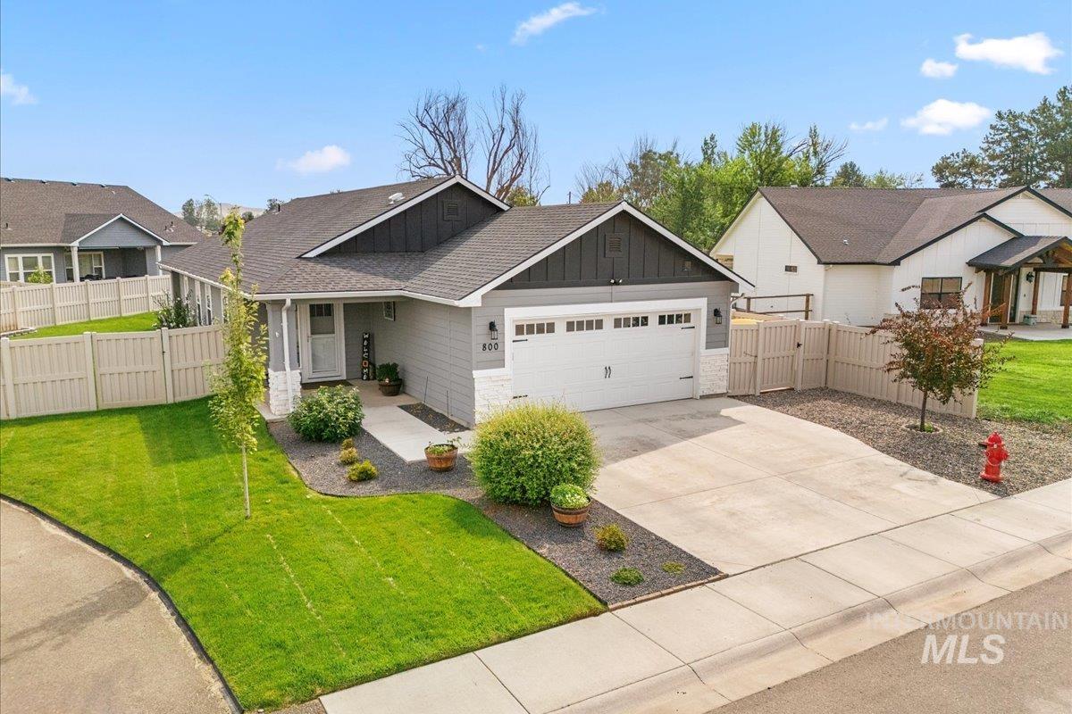 View of front facade with board and batten siding, concrete driveway, covered porch, a garage, and a residential view