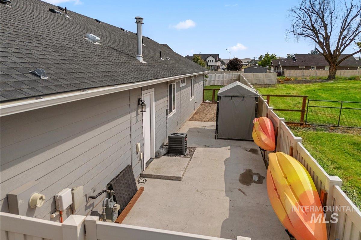 View of side of home with a fenced backyard, a shingled roof, a patio, and a residential view