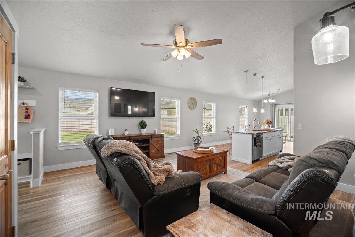 Living area with light wood-style floors, a textured ceiling, ceiling fan, lofted ceiling, and a chandelier